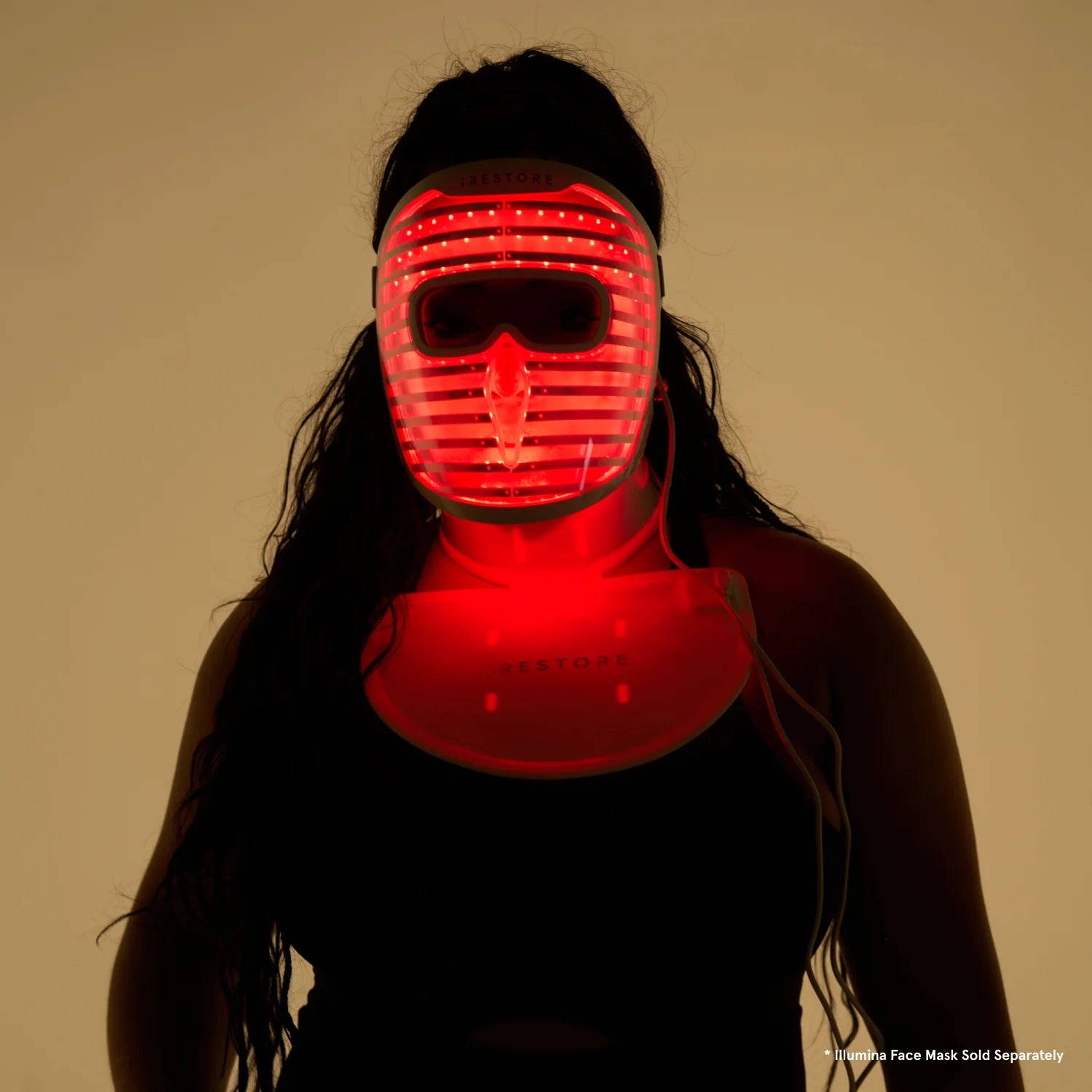 Silhouette of a woman wearing both the LED face mask and LED neck and chest mask with red light turned on. Disclaimer below saying 
