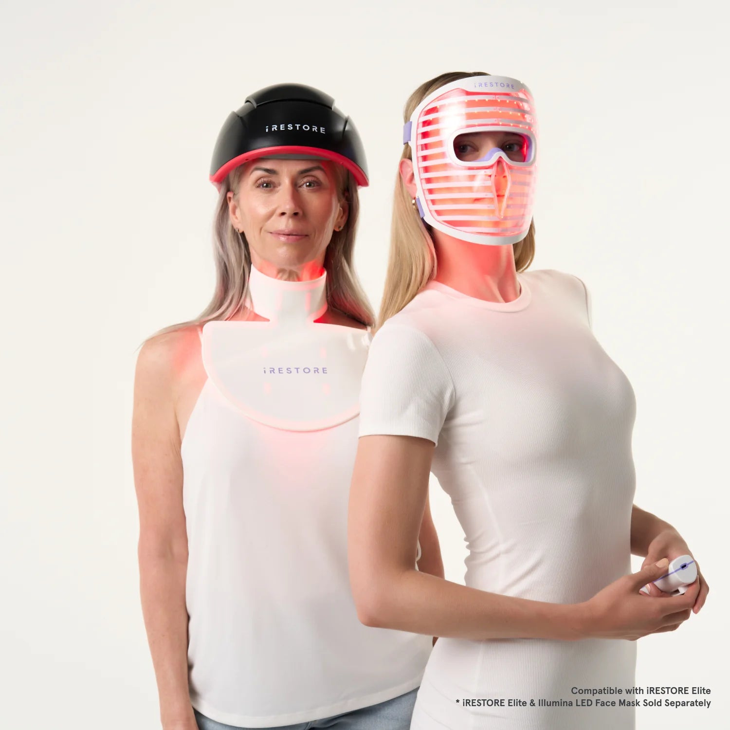 Two woman standing beside each other. The mature woman on the left is wearing the Elite Hair device and the LED neck and chest mask. The woman on the right is wearing the LED face mask